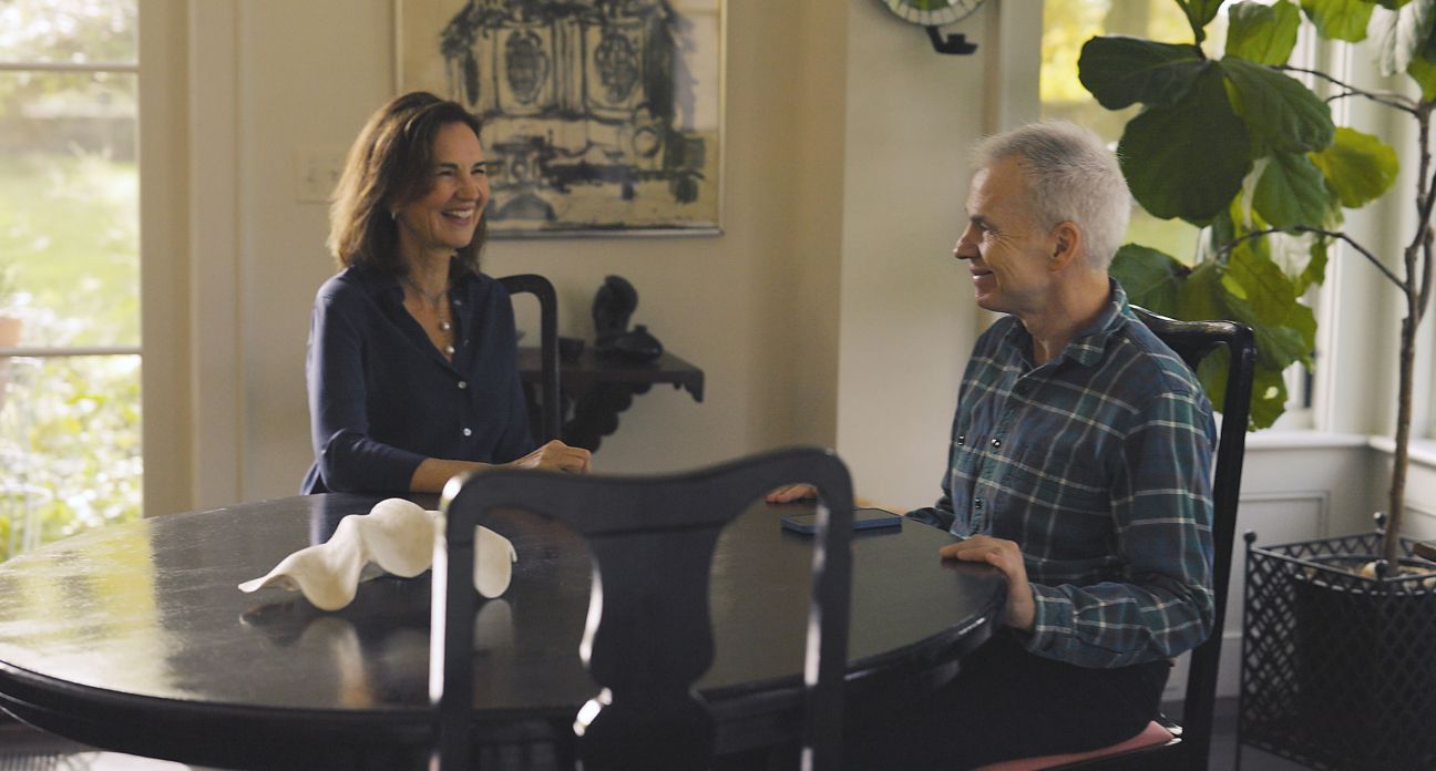 A man and a woman laughing around a dining room table.